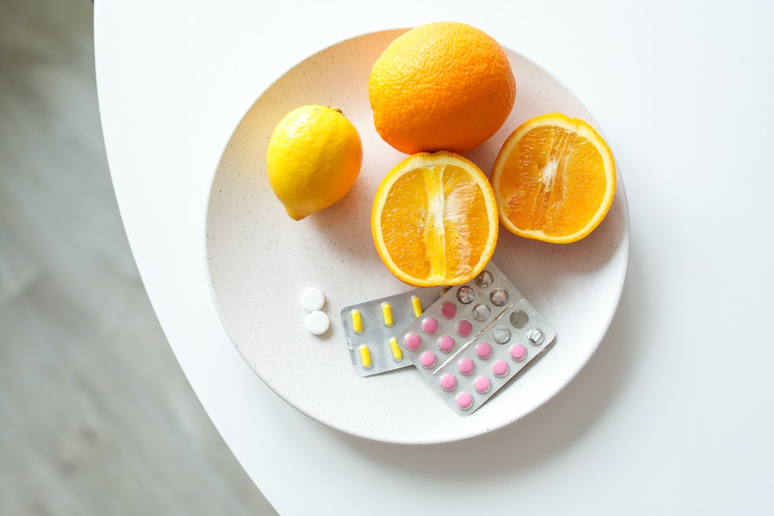 A white plate filled with oranges and pills