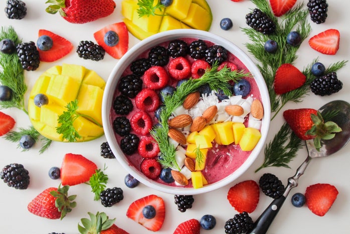 Pretty smoothie bowl surrounded by fruit.