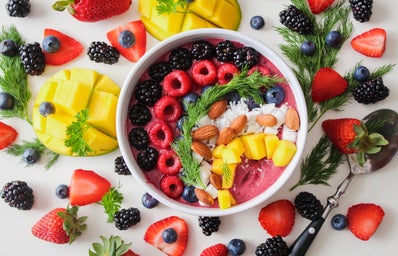 Pretty smoothie bowl surrounded by fruit.
