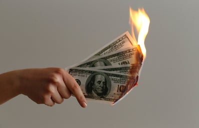 hand holding three 100 US dollars on fire