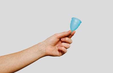 a hand holding a blue menstrual cup