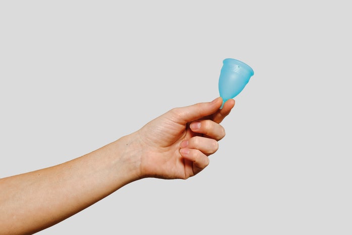 a hand holding a blue menstrual cup