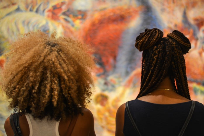Two black women with different natural hairstyles looking at art