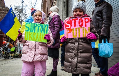 2 young girls protest war in Ukraine with signs