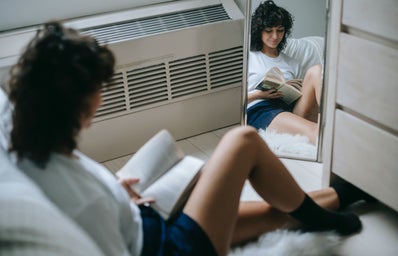Woman with book resting in bedroom