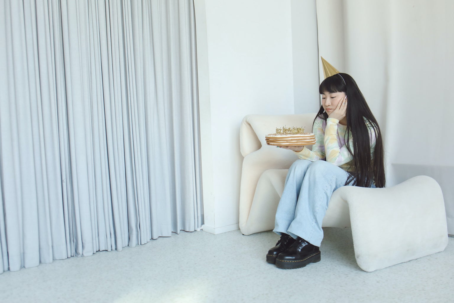 Woman sitting on couch looks at her birthday cake.
