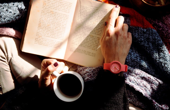 Person Reading Book and Holding Coffee