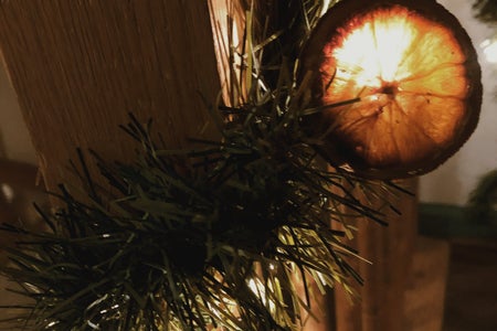 Orange Christmas garland strung around staircase with lights that illiumate the garland