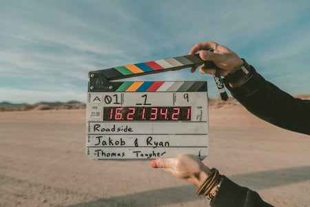 colorful "action" sign being held up by the hand of a director in the center of a desert