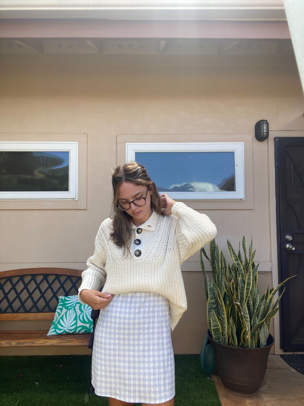 Woman posing looking at the ground with a blue dress and sweater on.