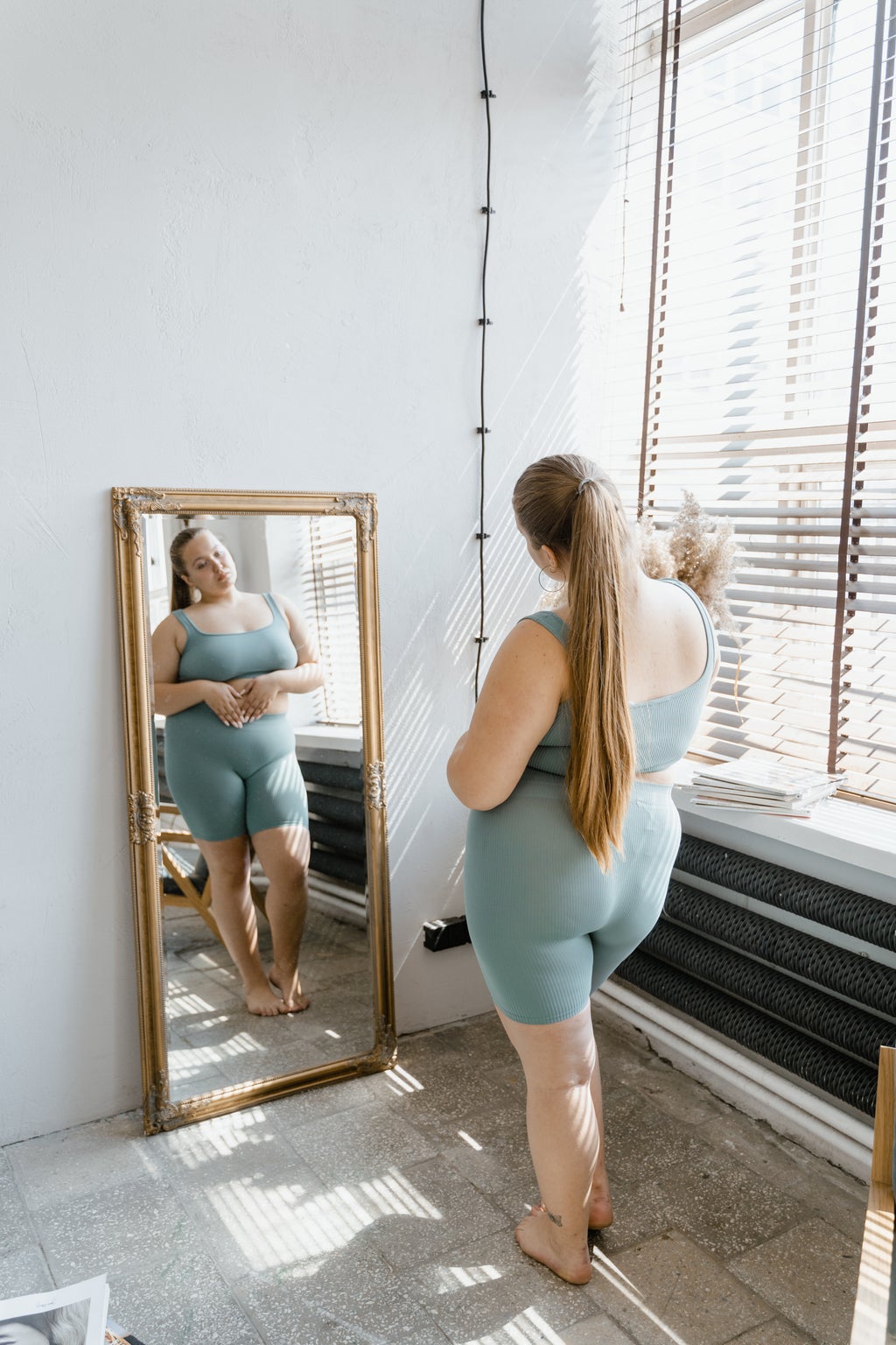 A woman in athletic clothes looks in the mirror.