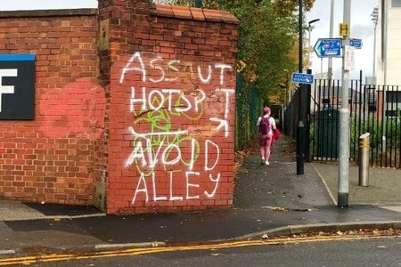 alleway wall with graffiti message on it