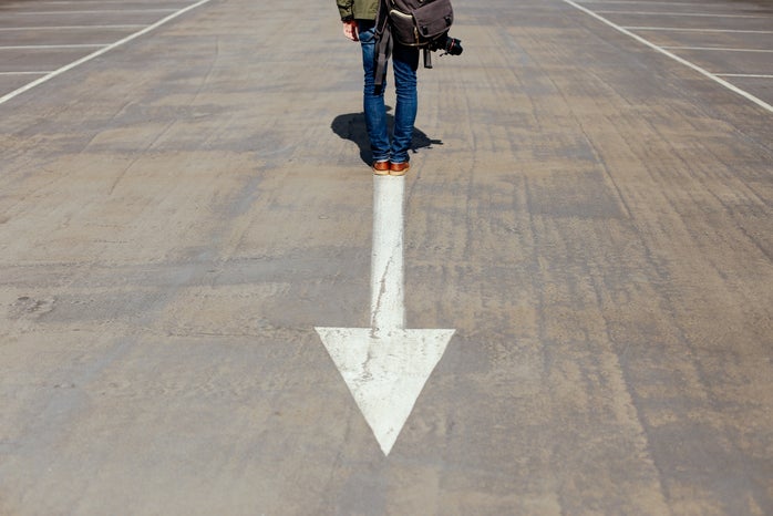 person standing on arrow sign on road by Smart via Unsplash?width=698&height=466&fit=crop&auto=webp