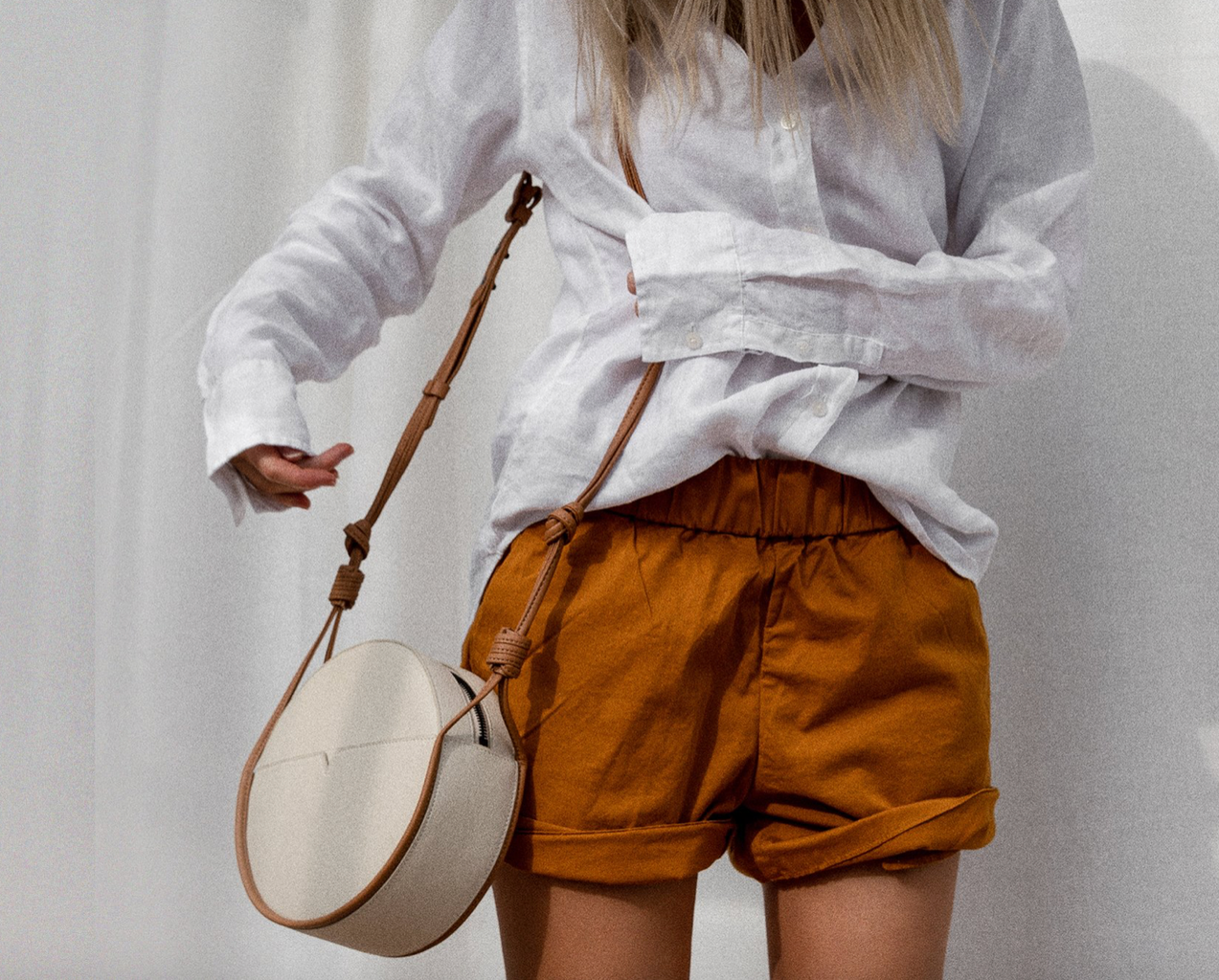 the von Holzhausen circular crossbody bag, woman carrying white and yellow bag over one of her shoulders