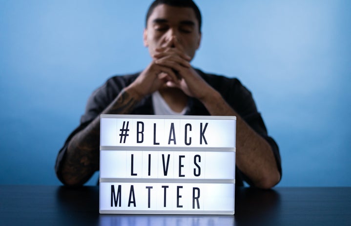 man behind a black lives matter sign