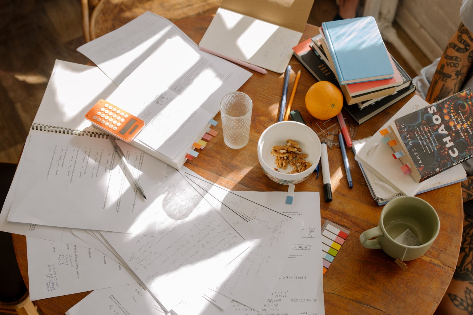books, paper, and a mug scattered on the table