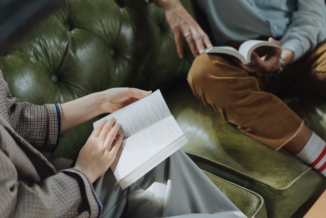 two people reading books on couch