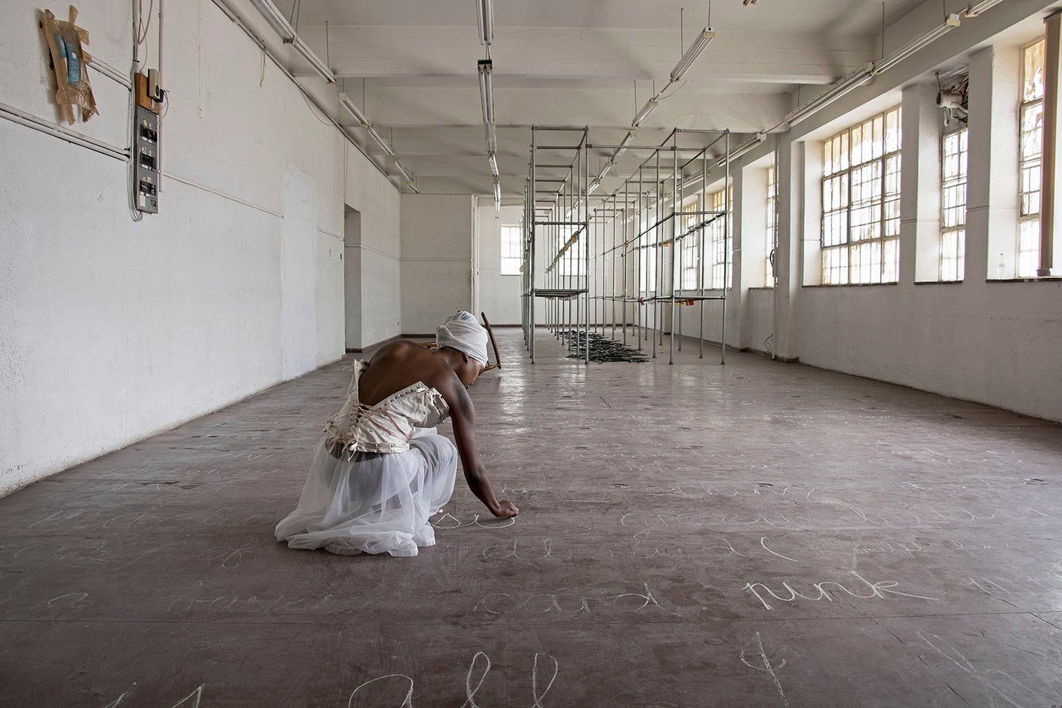 Buhlebezwe Siwani in white writing on floor in chalk in open white room
