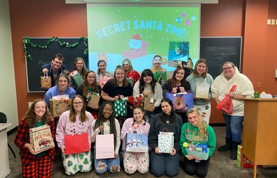 Her Campus Members at holiday party holding presents