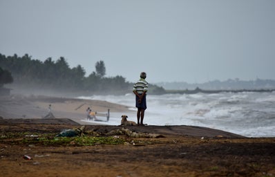 Man overlooking storm on beach.