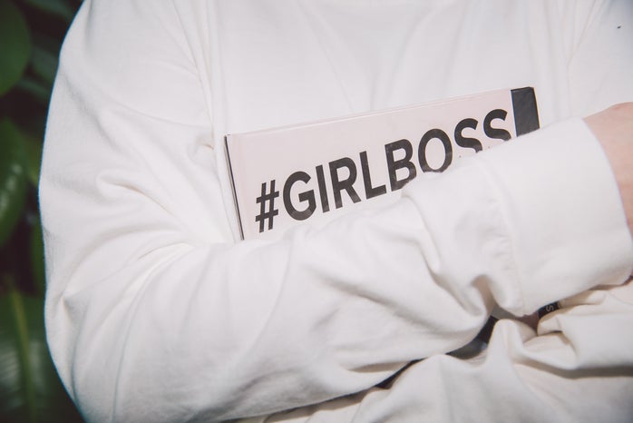 woman in long-sleeved shirt holding \"girlboss\" book