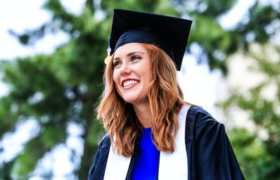 A woman smiles in her graduation cap and gown.