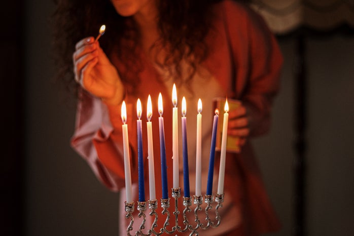 woman lighting blue and white candles on menorah