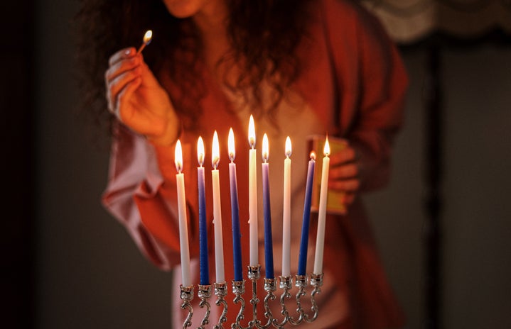 woman lighting blue and white candles on menorah