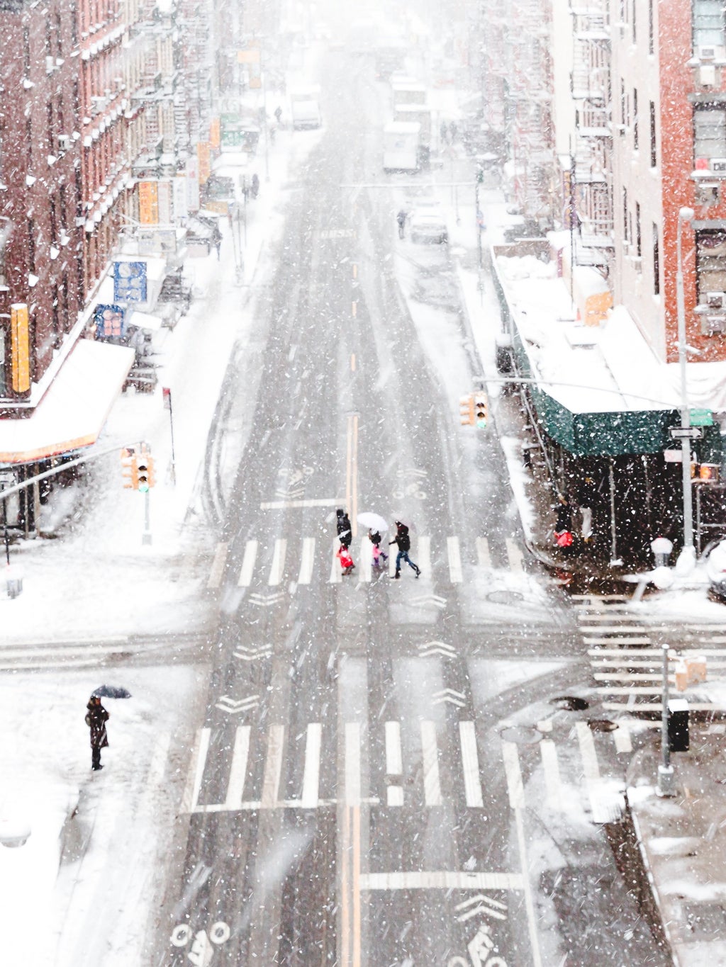 Snowy city with people walking in crosswalk