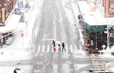 Snowy city with people walking in crosswalk