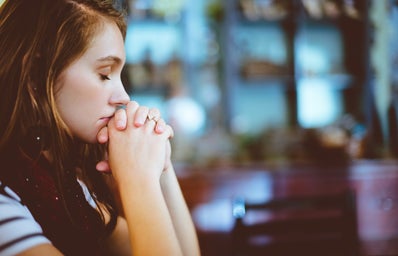 Girl with closed eyes and praying hands