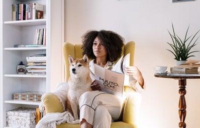 woman sitting with magazine and dog in the morning