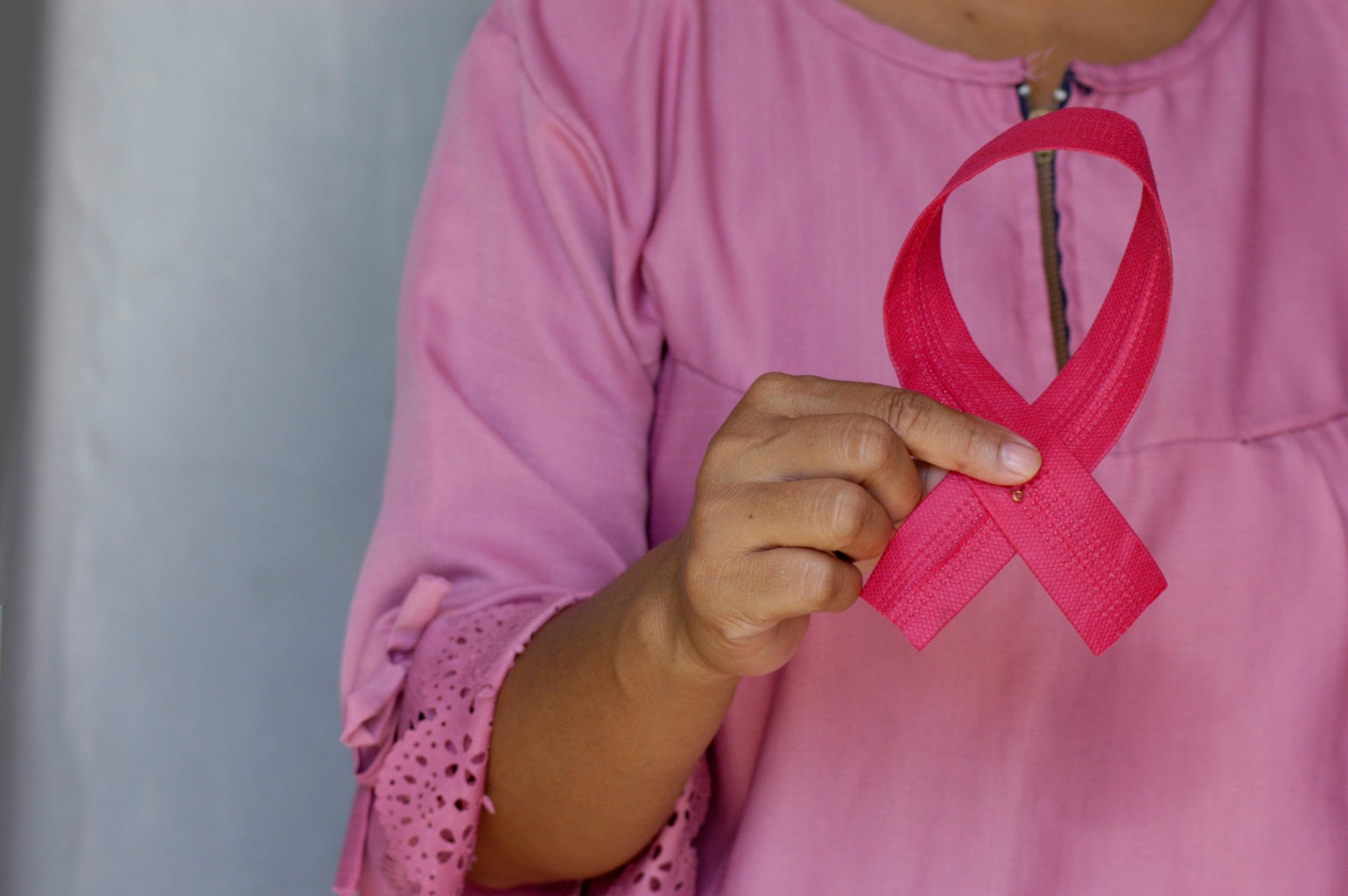 person holding pink breast cancer awareness ribbon