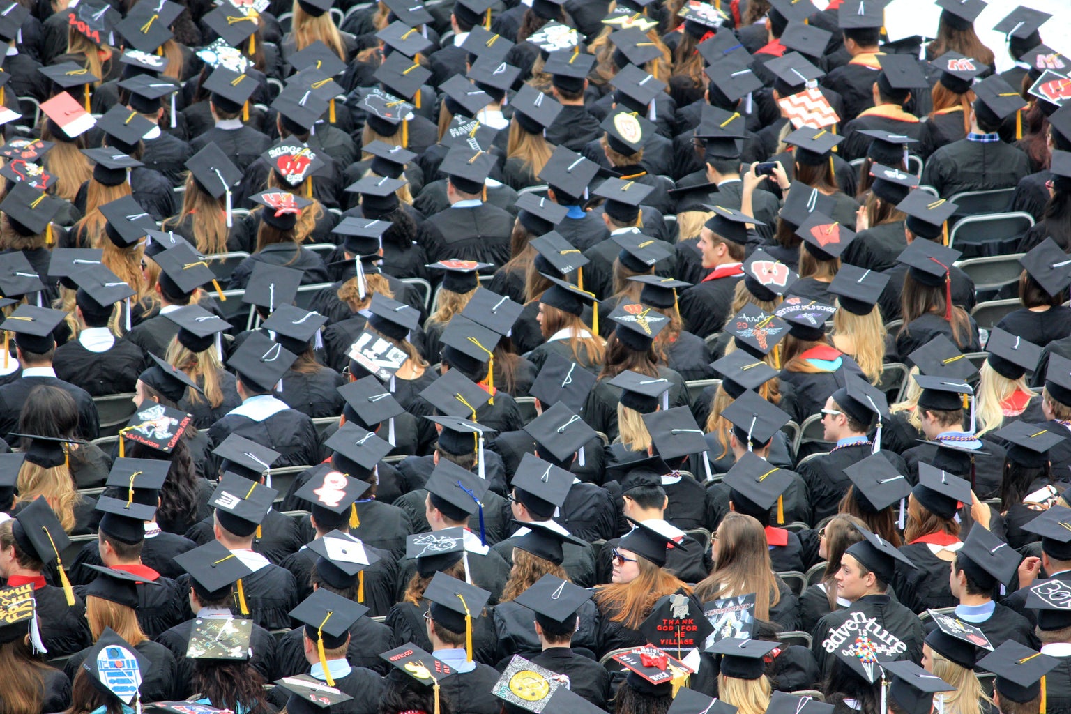a crowd of people sitting at a graduation all wearing graduation caps