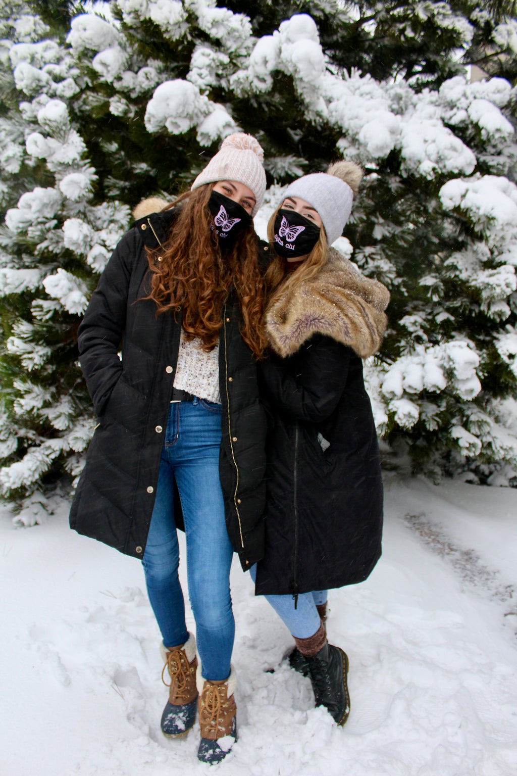 Two women posing for a picture in the snow on campus