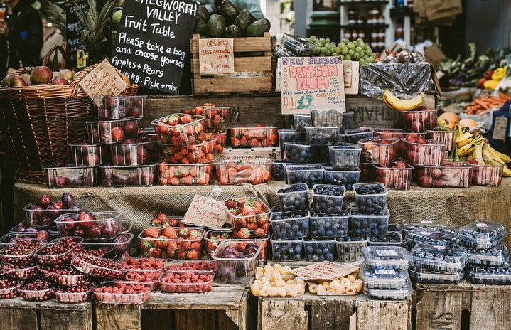 packaged fruits and signs set up at a booth at a farmer's market