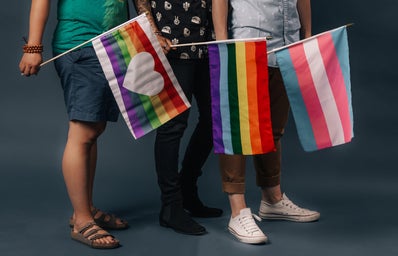Three people holding three different LGBTQ+ pride flags.