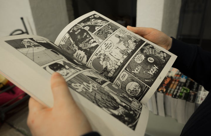 Hands holding a japanese comic book.