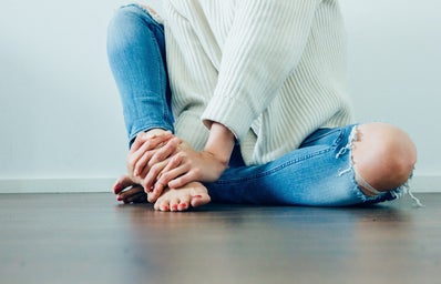 woman sitting on the ground with a white sweater and jeans