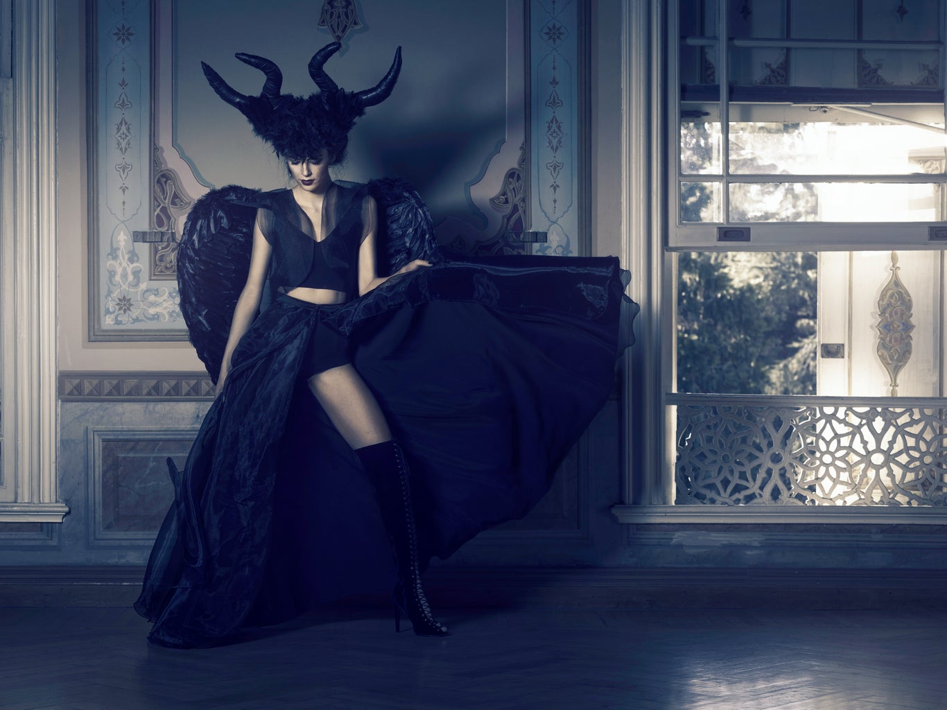 woman in black outfit with horns posing near window