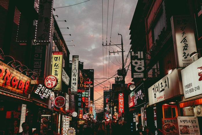 A landscape picture of a busy Korean street under a cloudy sky
