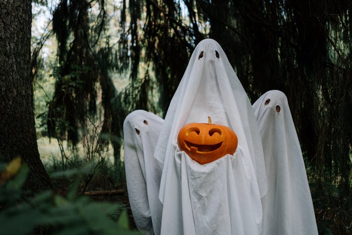three bed sheet ghosts with a pumpkin