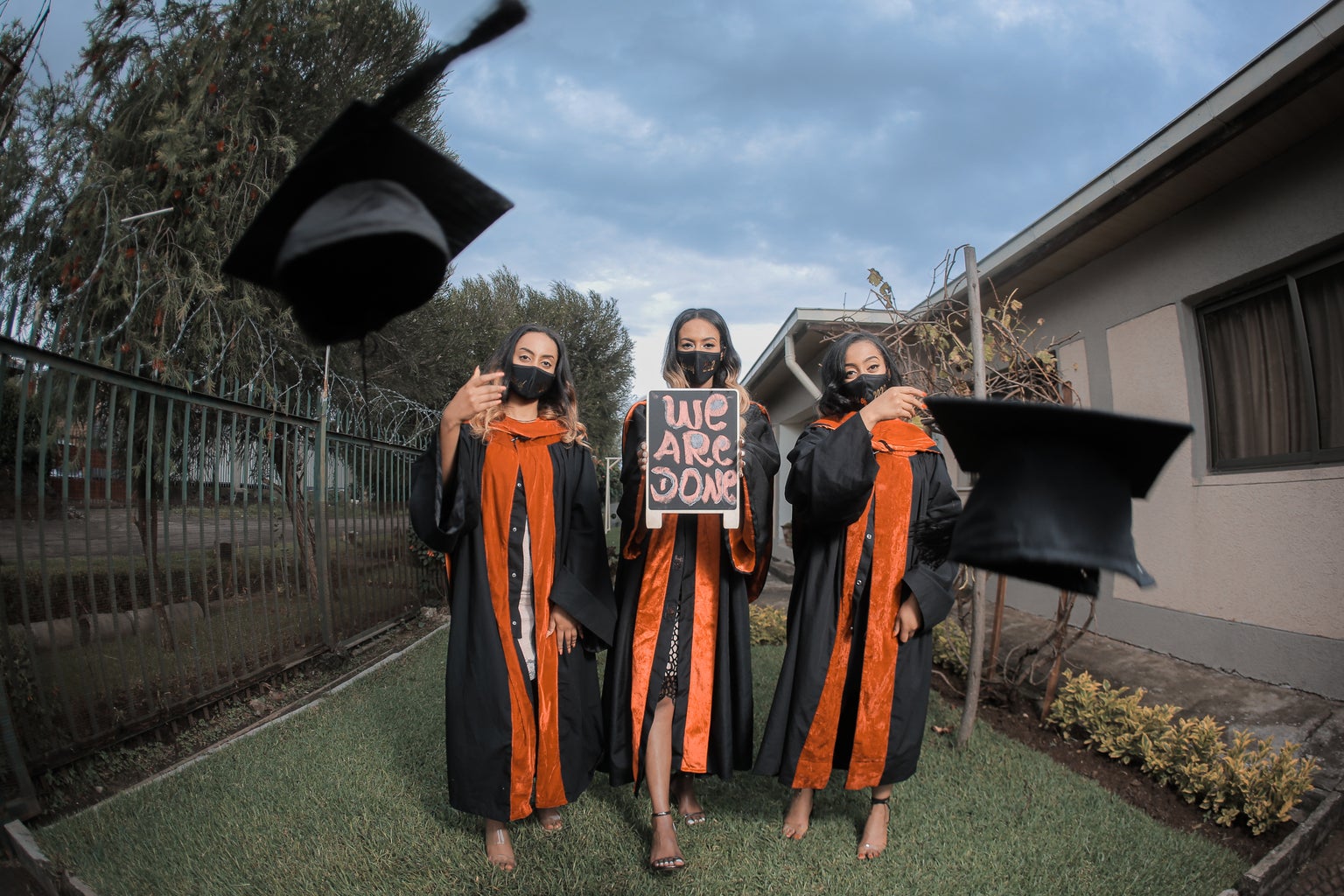 graduates wearing masks in cap and gowns