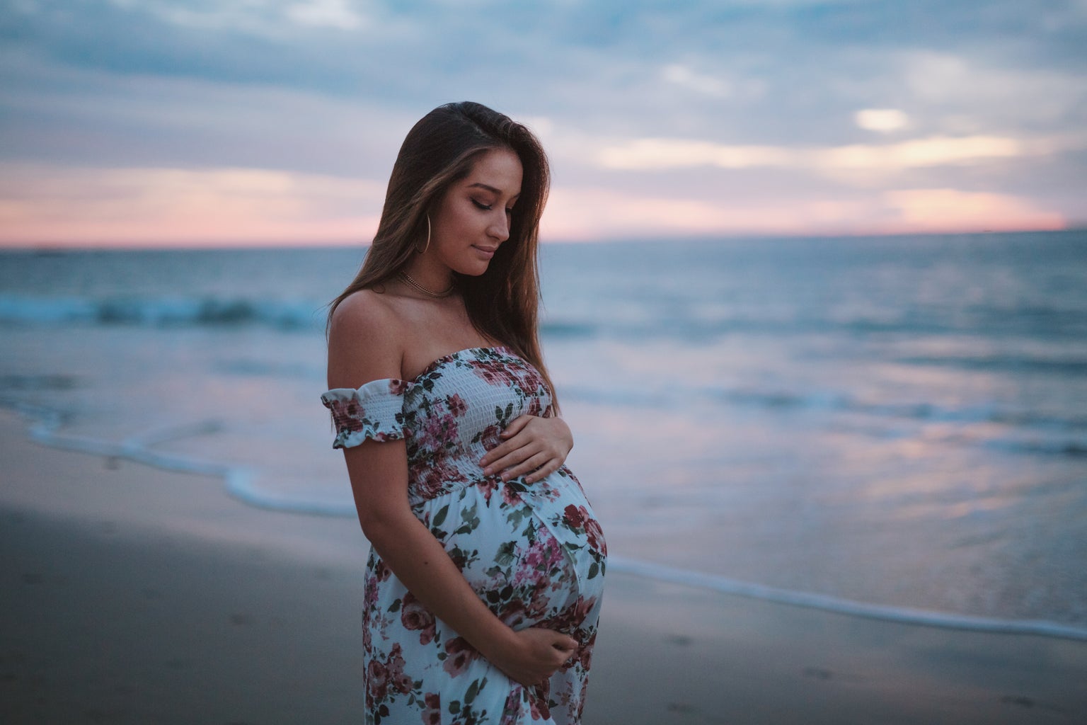 Pregnant woman on beach holding stomach