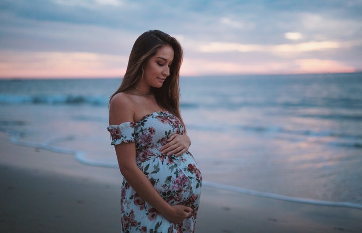 Pregnant woman on beach holding stomach by Neal Johnson on Unsplash?width=719&height=464&fit=crop&auto=webp