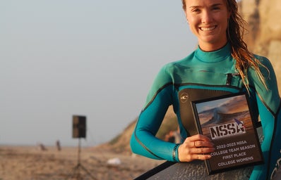 Woman at beach holding surfboard and plaque