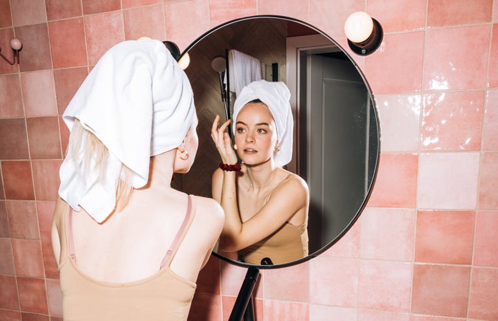 Woman in front of mirror doing skincare