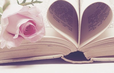 A flower on top of a books with pages folded into a heart