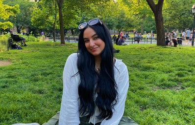 Safaa Salem sitting on grass with green pants and a white top