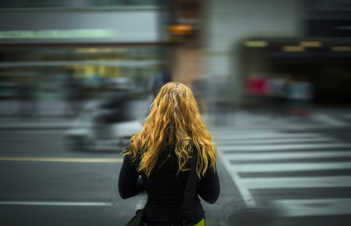 woman standing facing blurry street